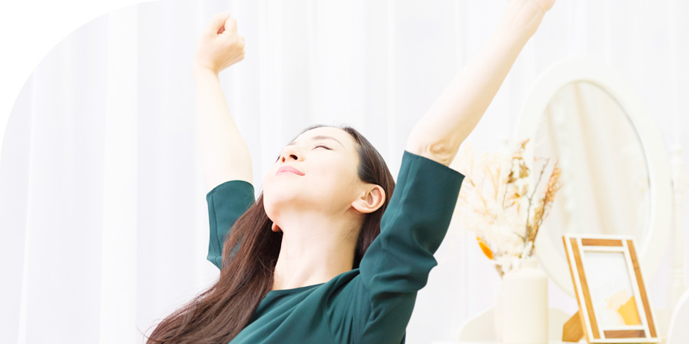 すっきりと伸びをしている女性のイメージ画像