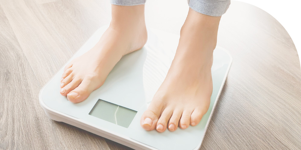 女性が体重計に乗るイメージ画像