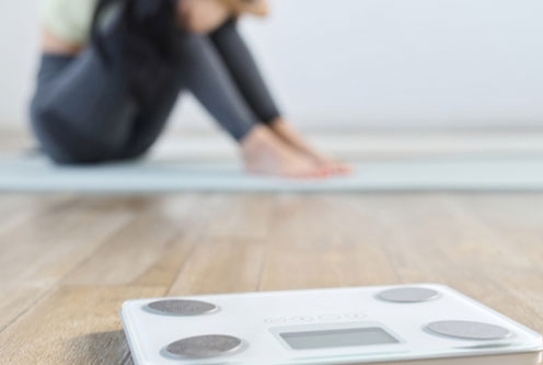 体重計と減量できず落ち込む女性のイメージ画像