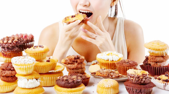 甘いお菓子を大量に食べる女性のイメージ画像
