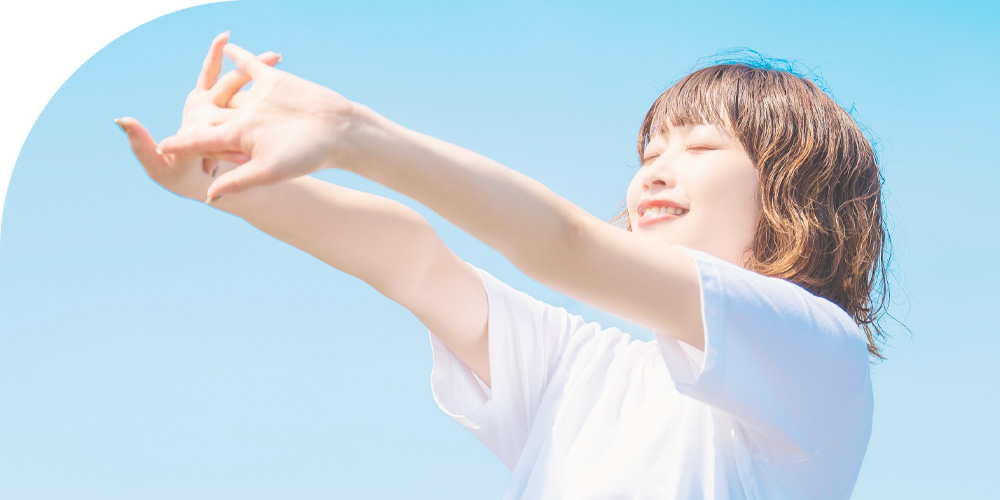 屋外で清々しく伸びをする女性のイメージ画像